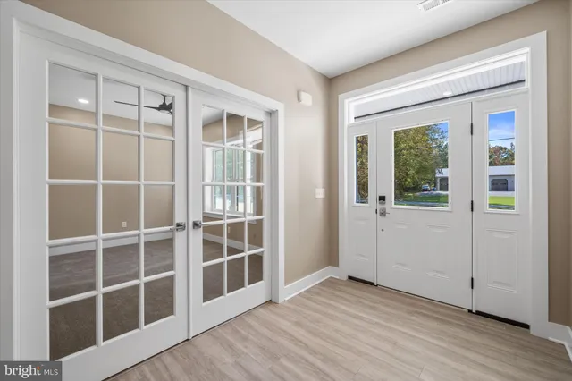a view of an empty room with wooden floor and windows