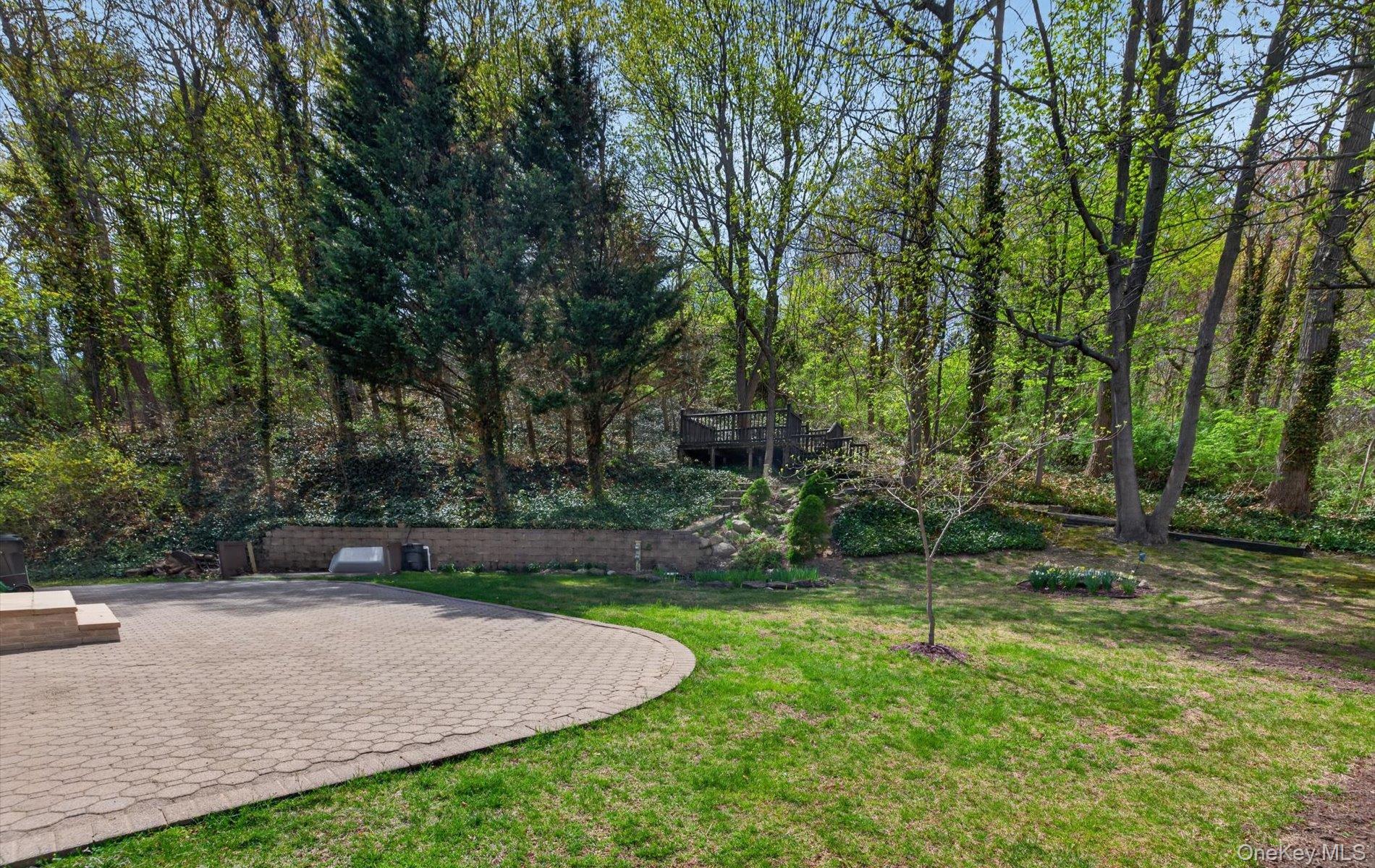 16 East Slope Road Bayville, NY 11709 - Photo 43 of 48 Expansive outdoor patio with paver surfacing, bordered by a manicured lawn