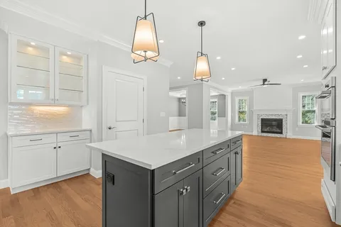 a large kitchen with kitchen island granite countertop a stove a sink a island and a wooden floors