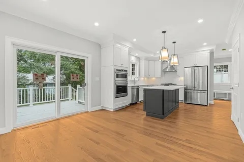 a view of kitchen with stainless steel appliances wooden floor and large window