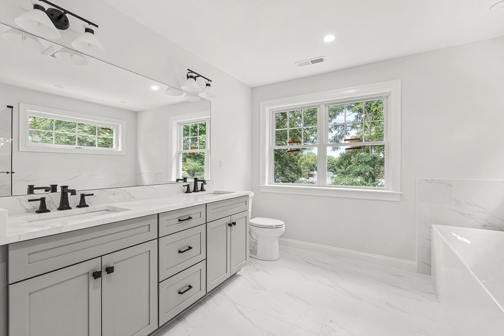 26 Flagg Street Woburn, MA 01801 - Photo 27 of 41 a bathroom with a granite countertop sink a large mirror a toilet and a window
