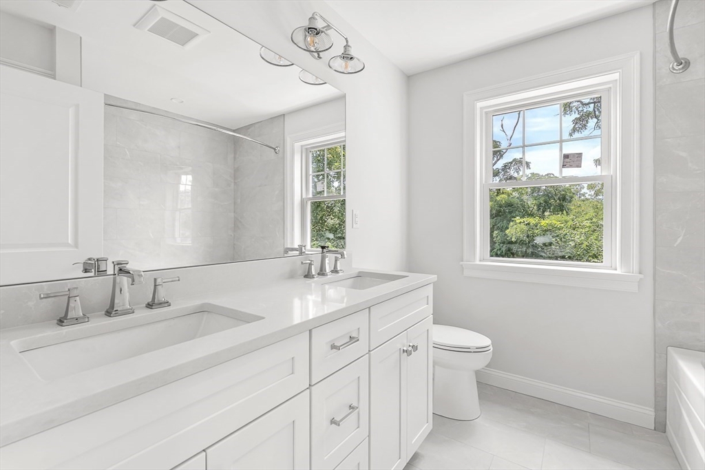 26 Flagg Street Woburn, MA 01801 - Photo 31 of 41 a bathroom with a granite countertop sink a large mirror a toilet and a window