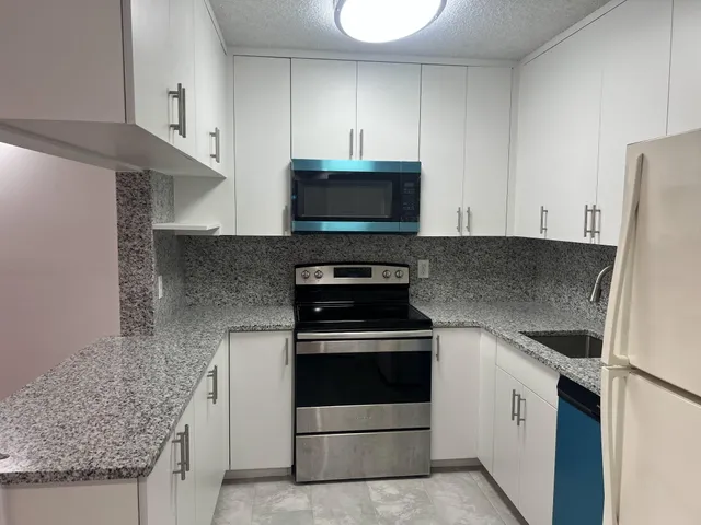 a kitchen with granite countertop white cabinets and stainless steel appliances