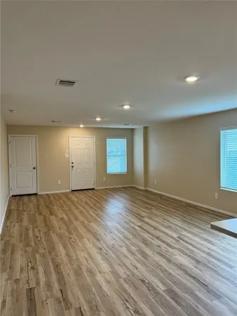 a view of an empty room with wooden floor and closet