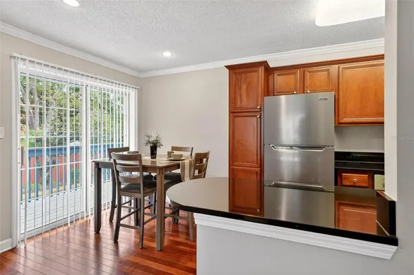 a kitchen with stainless steel appliances granite countertop a refrigerator a stove a dining table and chairs