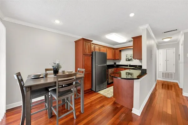 a kitchen with stainless steel appliances granite countertop a refrigerator a stove top oven a sink dishwasher and white cabinets with wooden floor