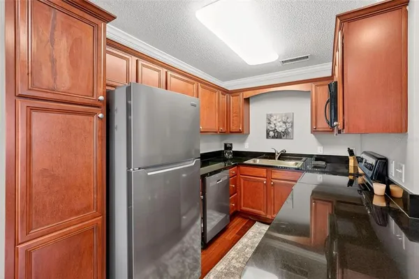 a kitchen with granite countertop stainless steel appliances a refrigerator a sink and cabinets