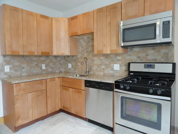 a kitchen with granite countertop white cabinets stainless steel appliances and a sink