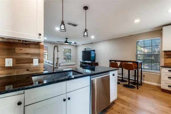 a kitchen with stainless steel appliances granite countertop a sink a stove and a wooden floors
