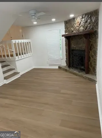 an empty room with wooden floor fireplace and windows
