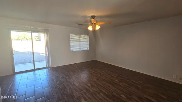 an empty room with wooden floor fan and windows