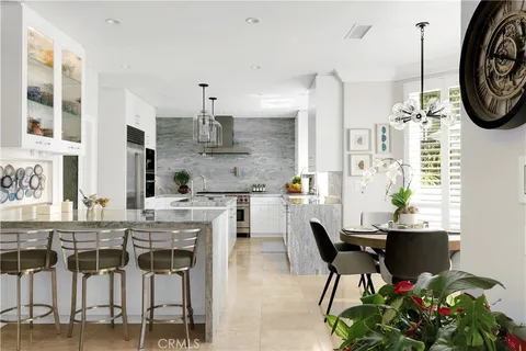 a kitchen with stainless steel appliances kitchen island granite countertop a dining table chairs and white cabinets