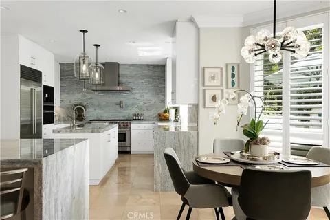 a kitchen with stainless steel appliances kitchen island granite countertop a table chairs in it and wooden floors