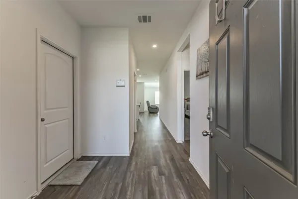 a view of a hallway with wooden floor and a bathroom