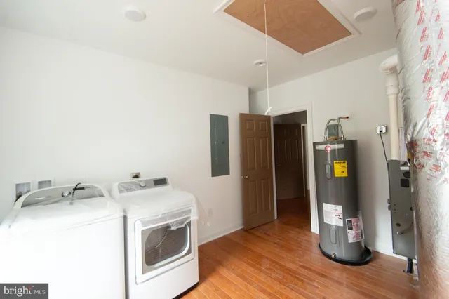 a living room with furniture a flat screen tv and a refrigerator