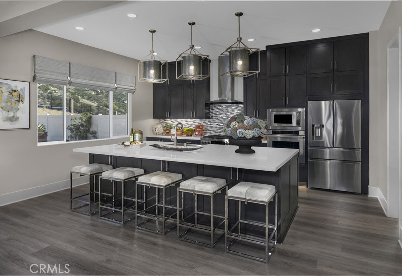 6517 Canyon Oaks Drive Simi Valley, CA 93063 - Photo 23 of 35 a kitchen with granite countertop a table chairs stainless steel appliances and wooden floor