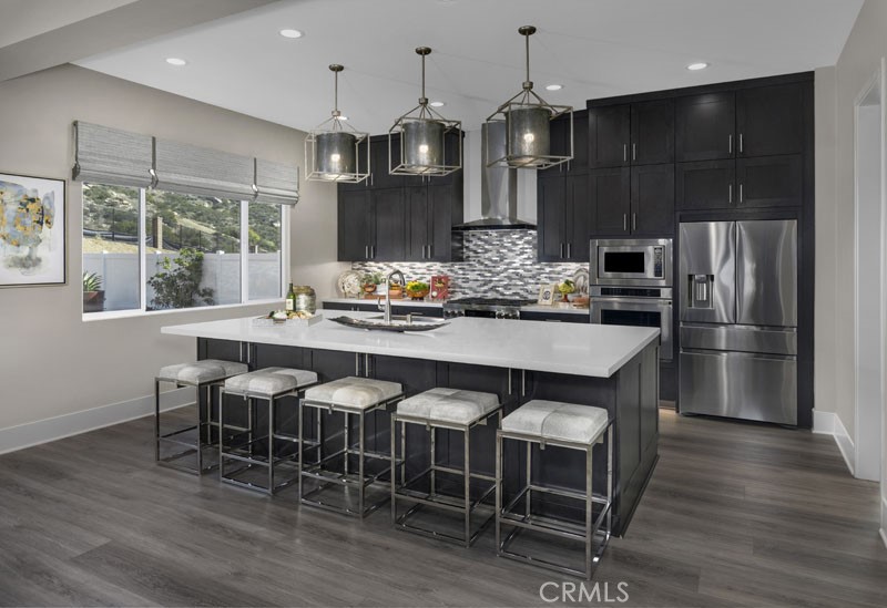6517 Canyon Oaks Drive Simi Valley, CA 93063 - Photo 6 of 35 a kitchen with granite countertop a table chairs stainless steel appliances and wooden floor