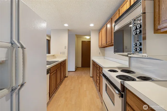 a kitchen with stainless steel appliances a sink a stove top oven a refrigerator and cabinets