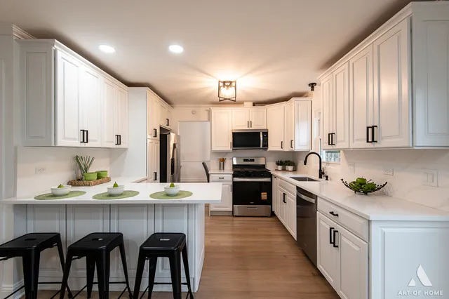 a kitchen with stainless steel appliances a kitchen island hardwood floor sink stove dining table and chairs