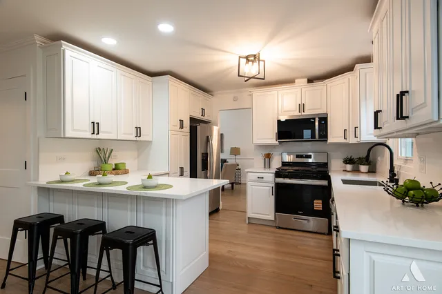 a kitchen with stainless steel appliances granite countertop a stove top oven a sink a refrigerator white cabinets and wooden floor