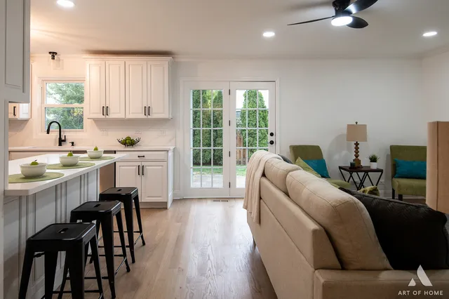 a living room with furniture a kitchen island wooden floor and a large window