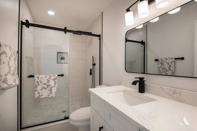 a bathroom with a shower sink vanity mirror and toilet