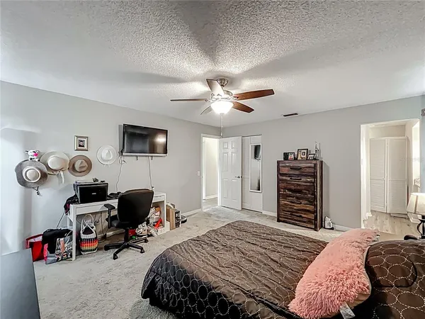 a bedroom with a bed a computer on a desk and dresser