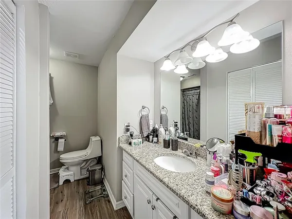 a bathroom with a granite countertop sink a toilet and a mirror