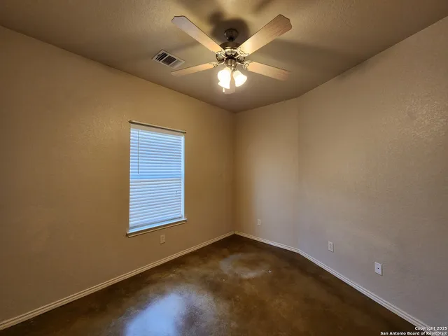 an empty room with a window and a ceiling fan