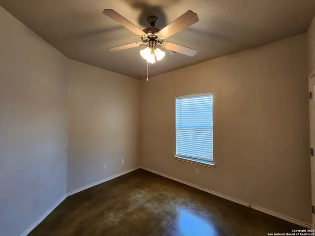 an empty room with windows and fan