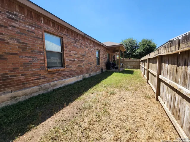 a view of a house with a small yard and wooden floor and fence