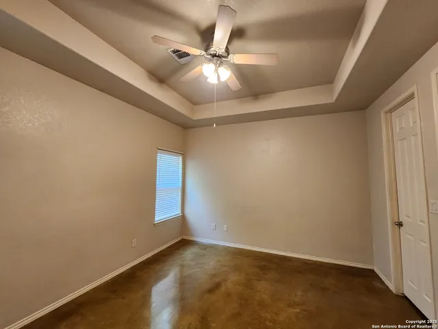 an empty room with ceiling fan and window