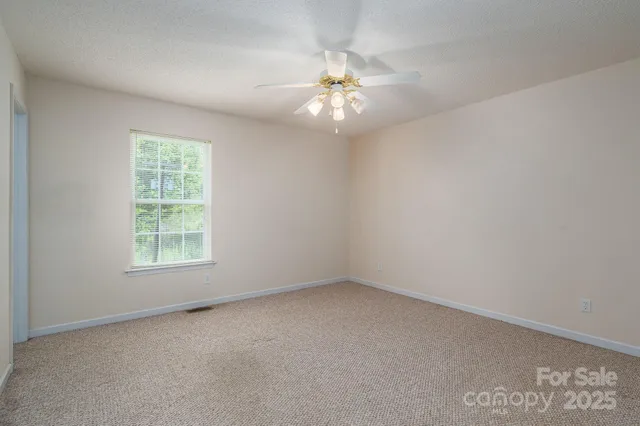 an empty room with a window and a fan