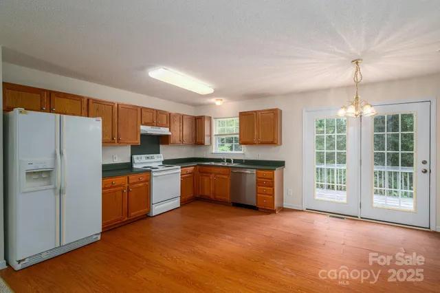 a large kitchen with stainless steel appliances granite countertop a refrigerator a sink dishwasher a stove with large countertops and wooden floor