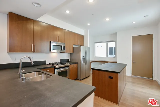 a kitchen with granite countertop a sink a stove a refrigerator cabinets and wooden floor