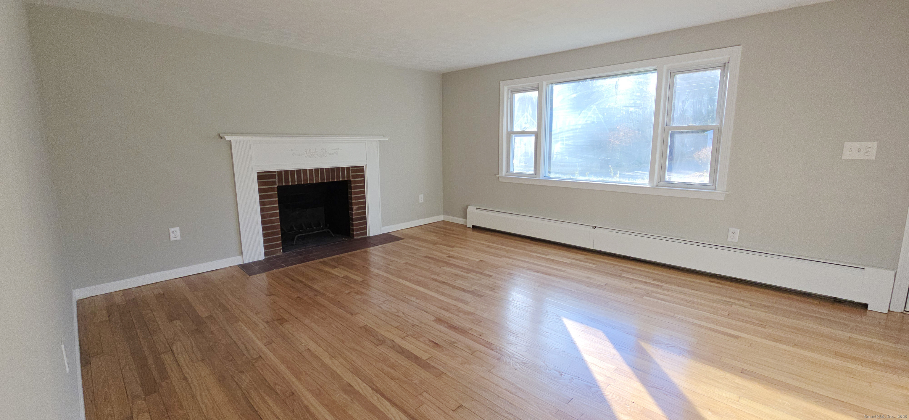 14 West Forrest Drive Enfield, CT 06082 - Photo 4 of 15 a view of an empty room with wooden floor fireplace and a window