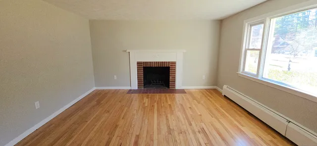 a view of an empty room with wooden floor and a window