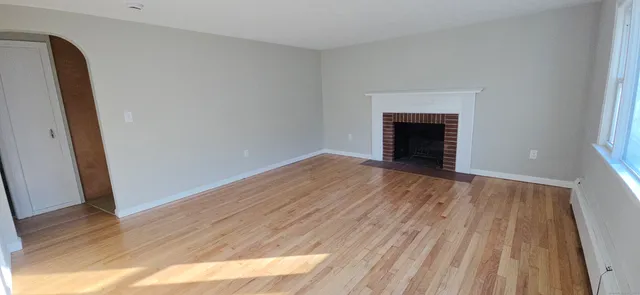 an empty room with wooden floor and fireplace
