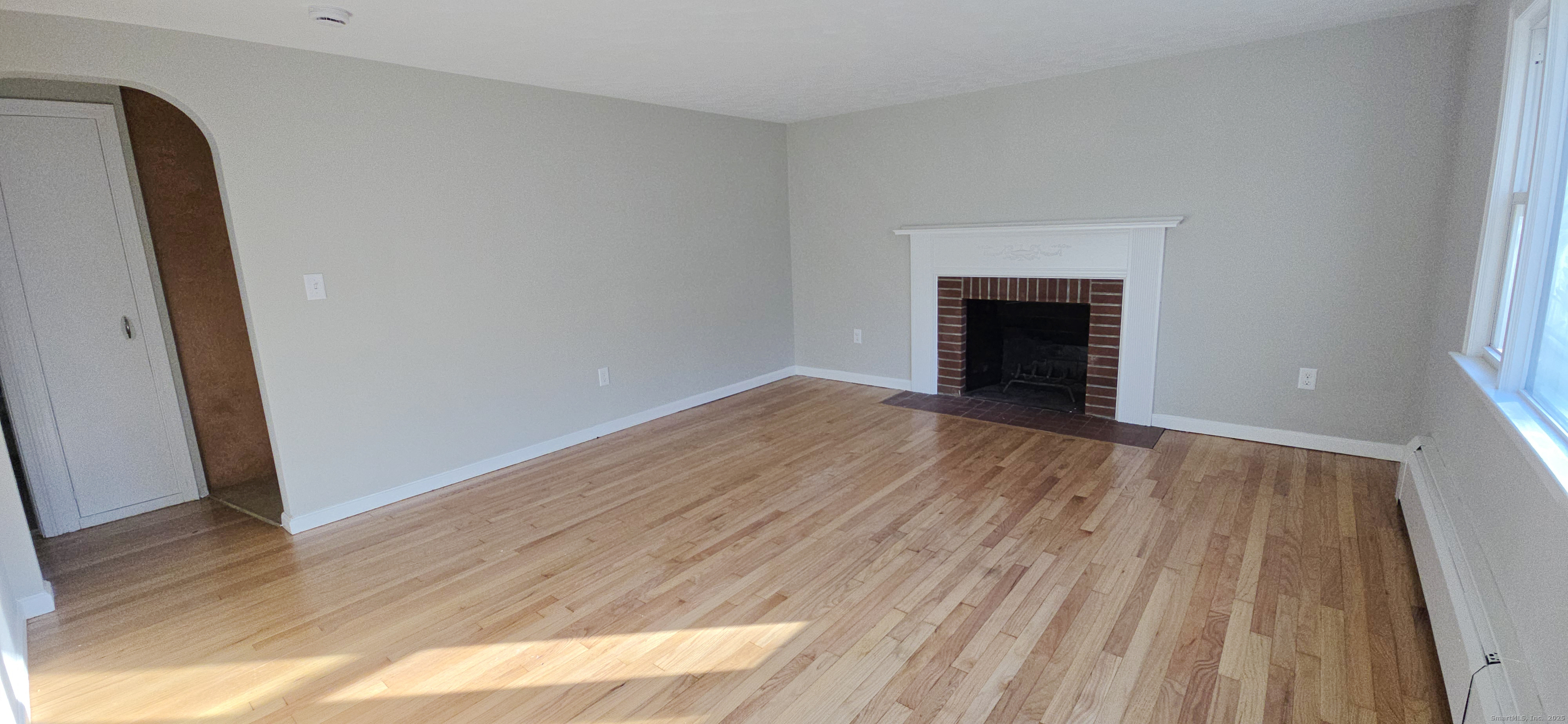 14 West Forrest Drive Enfield, CT 06082 - Photo 6 of 15 an empty room with wooden floor and fireplace