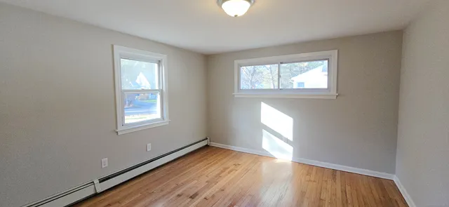 a view of empty room with wooden floor and fan