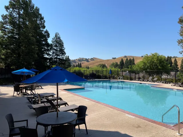 a view of a swimming pool with lawn chairs under an umbrella