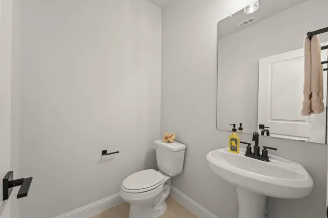 a view of a hallway with wooden floor and a toilet