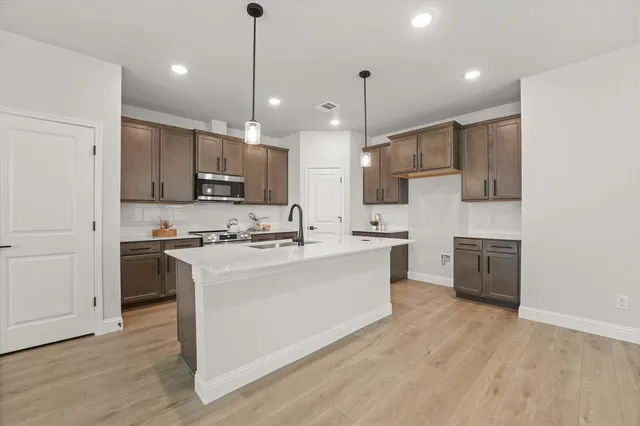 a large kitchen with stainless steel appliances kitchen island a cabinets and wooden floor