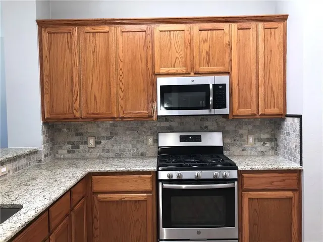 a kitchen with granite countertop a stove top oven microwave and cabinets