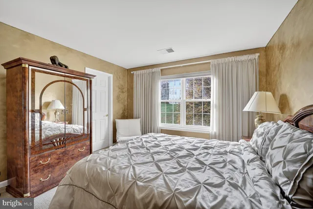 a bedroom with a bed and a large mirror next to a window