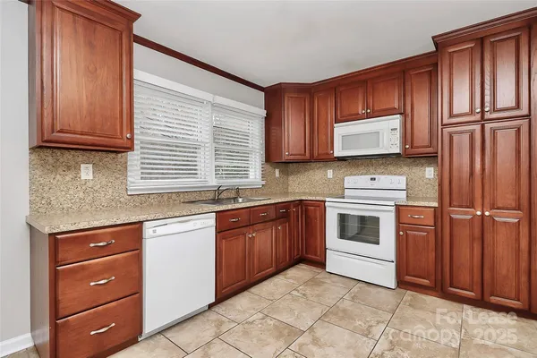 a kitchen with granite countertop wooden cabinets stainless steel appliances and a window