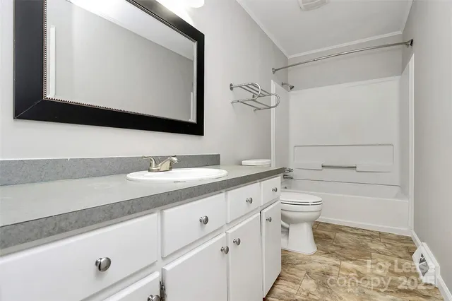 a bathroom with a granite countertop toilet sink and mirror