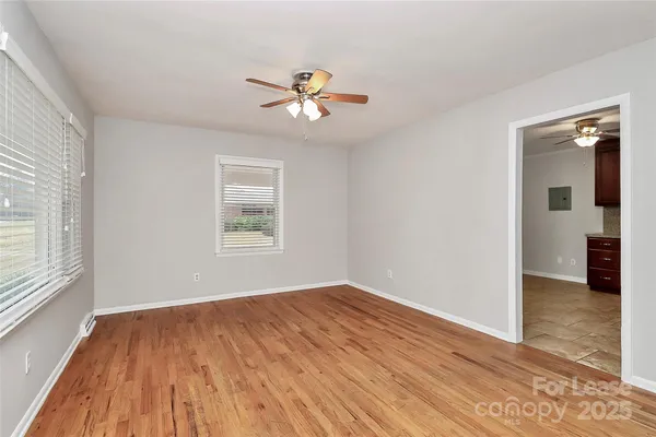 a view of empty room with wooden floor and fan