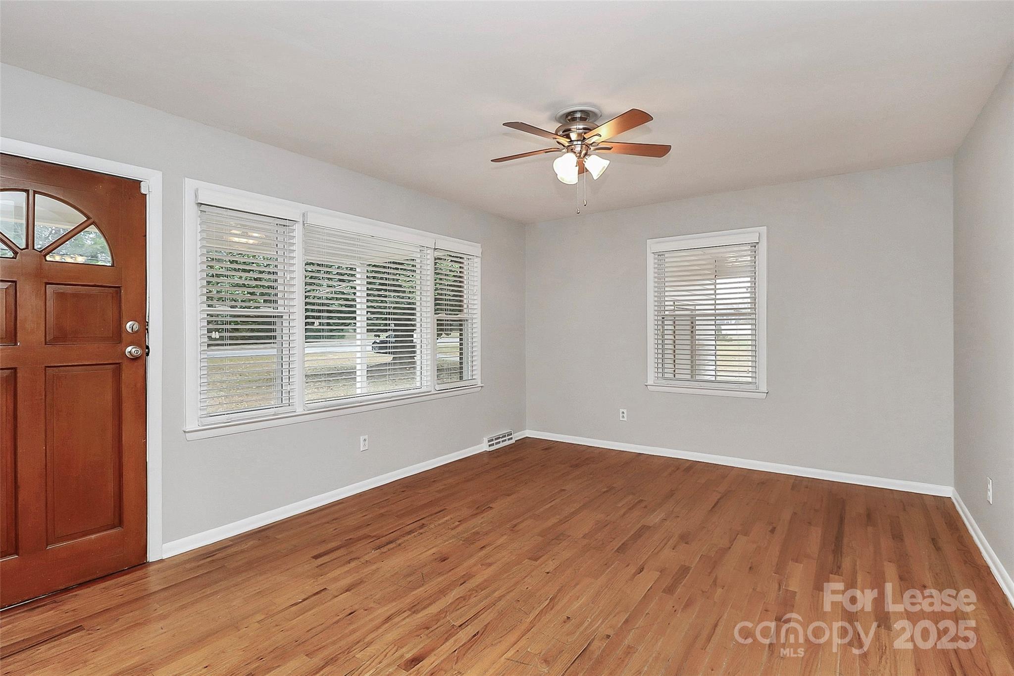8911 Reames Road Charlotte, NC 28216 - Photo 6 of 31 a view of empty room with wooden floor and fan
