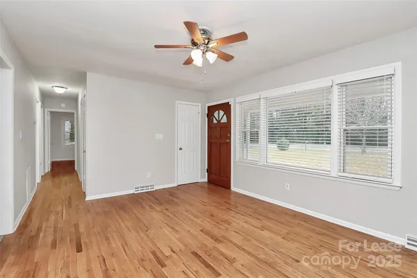 a view of an empty room with wooden floor and a window